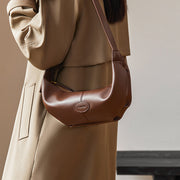 Brown genuine leather crossbody handbag with dumpling shape, soft texture, and single shoulder strap, perfect for women seeking luxury and functionality.