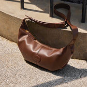 Brown genuine leather crossbody handbag with dumpling shape, soft texture, and single shoulder strap, perfect for women seeking luxury and functionality.